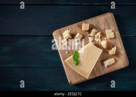 Zerbröckelter Parmesan-Käse, von oben auf einem dunkelblauen Holzhintergrund mit einem Platz für Text aufgenommen Stockfoto