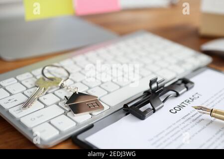 Hausschlüssel und Dokument mit Vertrag liegen auf der Tastatur Nahaufnahme Stockfoto