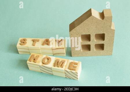 Haus Modell und Wort "Stay Home" Holzblöcke auf grünem Hintergrund. Rest, Self Quarantine, Virenschutzkonzept Stockfoto