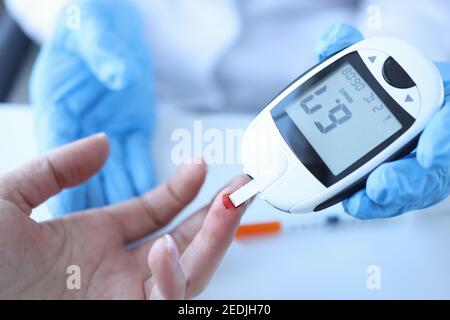 Arzt, der den Blutzucker des Patienten mit Glukosimeter in Nahaufnahme misst Stockfoto