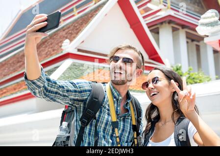 Junge Touristen Paar Rucksacktouristen, die Selfie mit dem Smartphone auf Ancient Thai Tempel auf Sommerferien in Bangkok Thailand Stockfoto