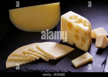 Verschiedene Käsesorten auf Steinplatte auf dunklem Hintergrund. Käsehintergrund. Stockfoto