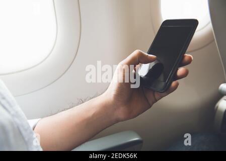 Männlicher Passagier, der das Mobiltelefon im Flugzeug abschaltet Flugsicherheit vor dem Flug Stockfoto