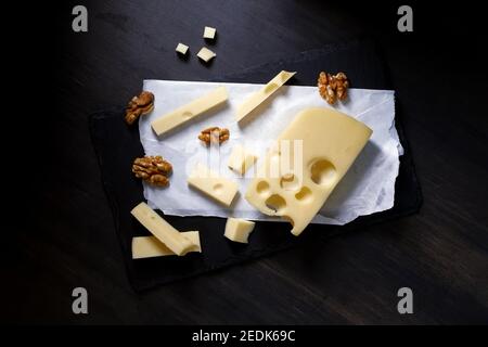 Käse in Scheiben geschnitten liegen auf Steinplatte Hintergrund. Draufsicht Stockfoto