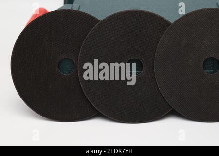 Schwarze Schleifscheibe, Schleifscheibe auf dem Hintergrund der grünen Werkzeugkiste. Abrasive Materialien, Scheiben, Werkzeuge in Nahaufnahme Stockfoto
