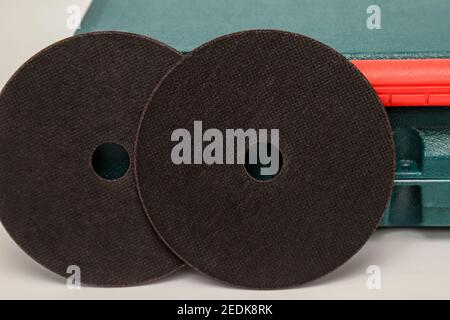 Schwarze Schleifscheibe, Schleifscheibe auf dem Hintergrund der grünen Werkzeugkiste. Abrasive Materialien, Scheiben, Werkzeuge in Nahaufnahme Stockfoto