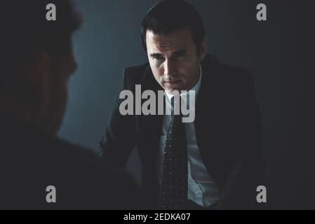 Detective interviewing Verdächtigen oder kriminellen Mann im Verhörraum Stockfoto