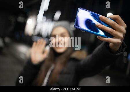 Ein schönes Mädchen winkt an einer Smartphone-Kamera Stockfoto