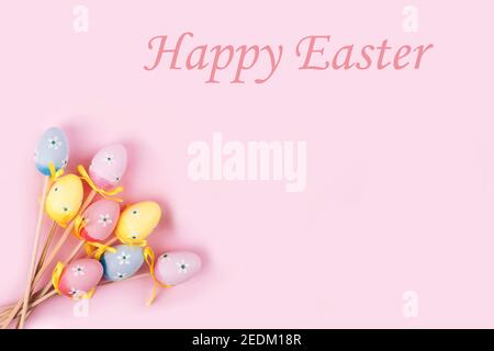 Bunte Ostereier auf rosa Hintergrund. Draufsicht mit Kopierbereich. Text Frohe Ostern auf der Oberseite. Stockfoto