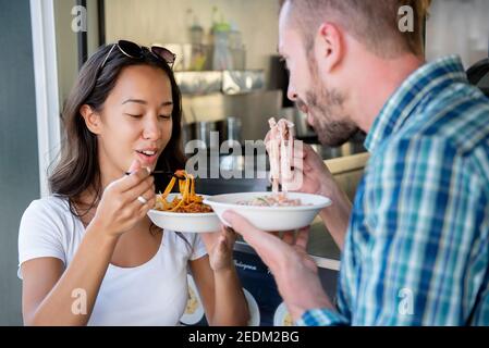 Junge interracial paar genießen essen Pasta aus Lebensmittel-LKW Stockfoto