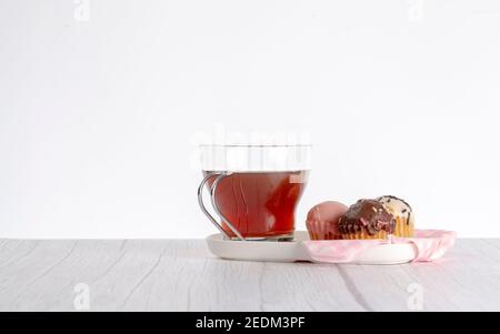 Cupcakes in verschiedenen Geschmacksrichtungen und Farben, begleitet von einer Tasse Tee Stockfoto