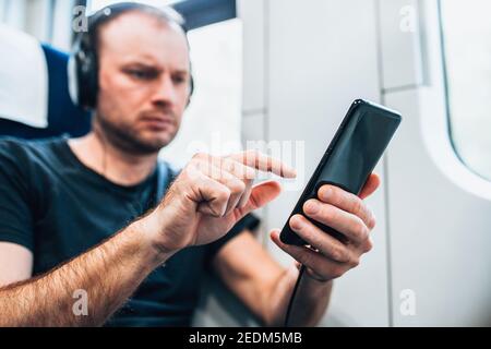 Persönliches Gadget in der Hand eines Mannes, der vorbei reist Train - Online-Kino und Musik - ein E-Book lesen Stockfoto