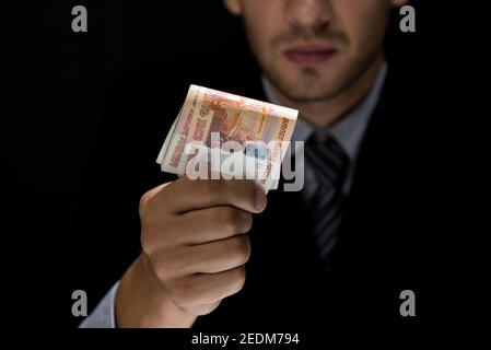 Geschäftsmann heimlich verschenken Geld in Form von russischen Rubel Währung im Dunkeln - Bestechung, Betrug und Korruption Konzepte Stockfoto