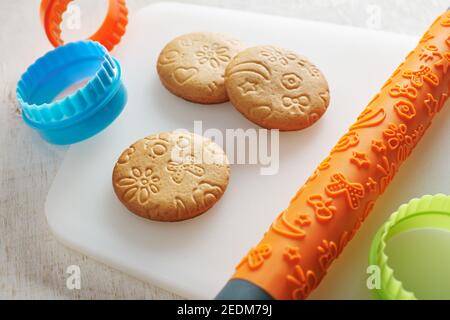 Cookies, Prägezapfen und Ausstechformen auf einer weißen Schneidebrett Stockfoto