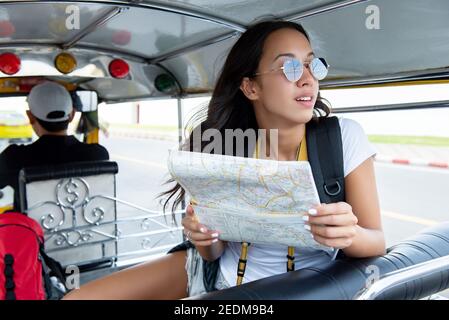 Junge unabhängige Frau Touristen, die mit lokalen Tuk Tuk Taxi Erkunden Sie die Stadt in Bangkok Thailand auf Sommerferien Stockfoto