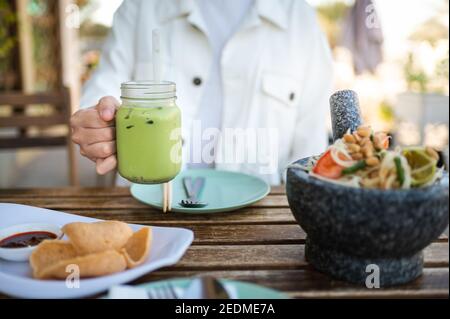 Frau mit grünem Tee während einer Mahlzeit in einem Thai Restaurant in der Nähe Stockfoto