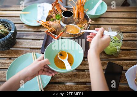 Frau mit Thai Tom Yum Suppe mit Garnelen und Krabben In einem Restaurant First Person Blick Stockfoto