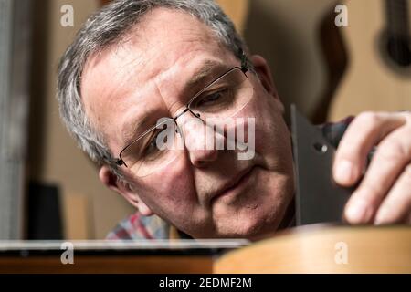 Der walisische Gitarrenbauer Paul Beauchamp arbeitet an einer handgefertigten Akustikgitarre in seiner Werkstatt in Roath, Cardiff Stockfoto