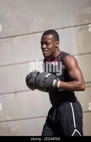 Portrait muskulösen schwarzen Profi-Boxer Schwitzen mit Handschuhen, um sein Boxtraining im Freien zu starten. Boxen und Training Konzept 2021. Stockfoto