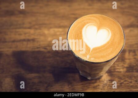 Schöne herzförmige Latte Art Kaffee im Glas auf Holztisch mit Kopierplatz Stockfoto