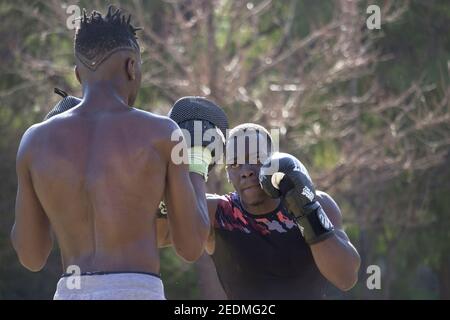 Professionelle Black Boxer trainiert Black Boxer Anfänger mit Boxhandschuhen einen Outdoor Boxkurs an einem sonnigen Tag, während sie beide schwitzen. Boxkonzept. Stockfoto