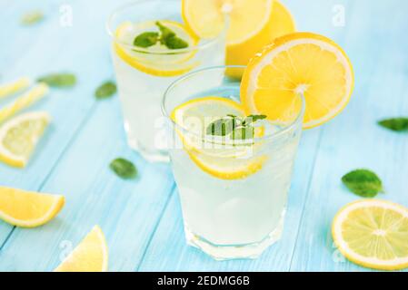 Erfrischende Getränke für den Sommer, kalter süßer und saurer Limonensaft mit Eiswürfeln in den Gläsern garniert mit frisch geschnittenen Zitronen Stockfoto