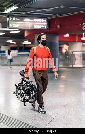 Stock Foto von Mann trägt Gesichtsmaske wegen covid19 Gehen und Tragen seines Fahrrads. Stockfoto