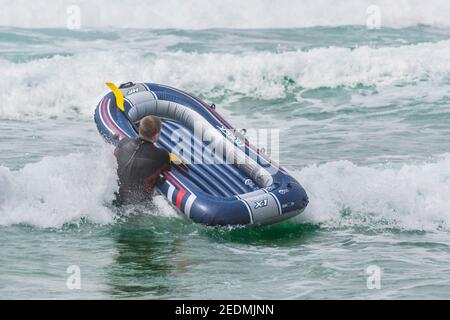 Ein Urlauber mit einem Schlauchboot auf Fistral; Beach in Newquay in Cornwall. Stockfoto