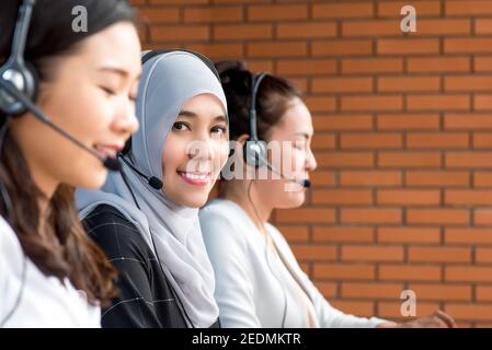 Lächelnd schöne asiatische muslimische Frau Kundenservice-Betreiber arbeiten in Call Center mit ihrem Team Stockfoto