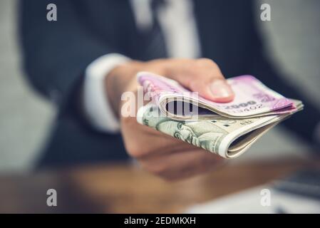 Geschäftsmann, der Geld in Form von indischen Rupien Währung Für erbrachte Dienstleistungen Stockfoto