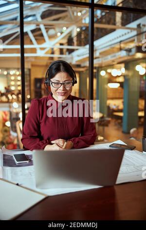 Konzentrierte Brünette arbeitet mit ihrem Team online Stockfoto