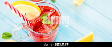 Bunte Erfrischungsgetränke für den Sommer, kalter Erdbeer-Limonensaft mit Eiswürfeln in der Glasse garniert mit frisch geschnittener Zitrone Stockfoto