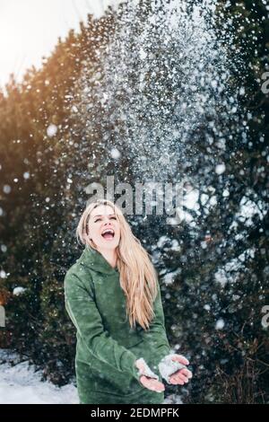 Junge fröhliche Blondine im Winter mit Spaß mit Schnee - Schneebälle werfen und lachen - glückliches neues Jahr Tage zuvor weihnachten Stockfoto
