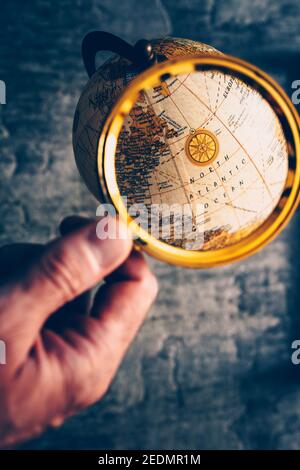 Die Erkundung des Planeten Erde auf einem geografischen Globus durch eine Lupe Glas Stockfoto