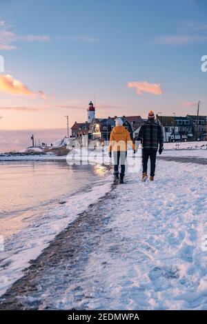 Paar Männer und Frauen am Leuchtturm von Urk Niederlande im Winter im Schnee. Winterwetter in den Niederlanden von Urk Stockfoto