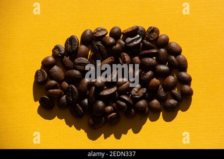 Dunkel geröstete Kaffeebohnen auf bunt orange Hintergrund Frühstück Thema Stockfoto