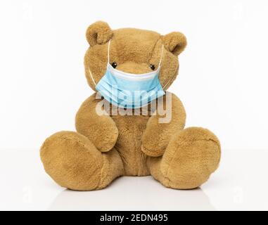 Brauner pelziger Teddybär mit isolierter Gesichtsmaske Ein weißer Hintergrund Stockfoto