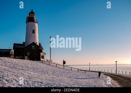 Schneebedeckter Strand während wnter von Urk Leuchtturm in den Niederlanden. Kaltes Winterwetter in den Niederlanden Stockfoto