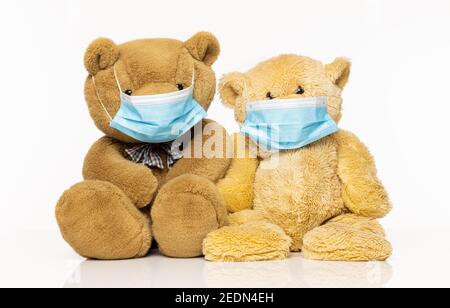 Zwei Teddybären tragen Gesichtsmasken isoliert auf einem weißen Hintergrund Stockfoto