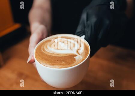 Eine große weiße Tasse Cappuccino in der Hand - ein Espresso-basierte italienischen Kaffee Getränk mit dem Zusatz von erwärmten Schaum Milch Stockfoto