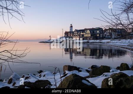 Schneebedeckter Strand während wnter von Urk Leuchtturm in den Niederlanden. Kaltes Winterwetter in den Niederlanden Stockfoto