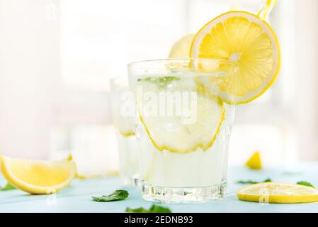 Erfrischende Getränke für den Sommer, kalter süß-saurer Limonensaft mit Eiswürfeln in den Gläsern garnieren mit Zitronenscheiben Stockfoto