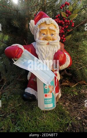 05,12.2020, Berlin, Deutschland - die Weihnachtsfigur hält einen Mund-Nase-Schutz in der Hand, unter einer Flasche mit Händedesinfektionsmittel. 00S2012 Stockfoto