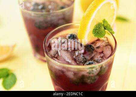 Erfrischende Getränke für den Sommer, kalter süßer und saurer Blaubeerlimonade-Saft in den Gläsern mit Zitronenscheibe Stockfoto