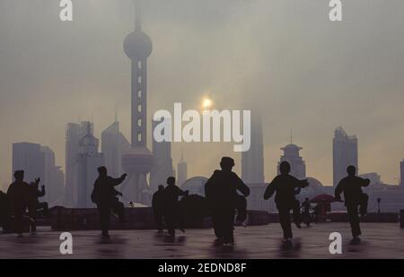 05,03.2011, Shanghai, , China - Tai Chi Übungen am frühen Morgen mit Blick vom Bund über den Huangpu Fluss auf die Skyline des Unternehmens Stockfoto