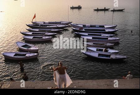 13,04.2014, Varanasi, Uttar Pradesh, Indien - Blick von einem Ghat am Ufer des heiligen Ganges auf Baden Menschen im Fluss und vorbei Ruderboote i Stockfoto
