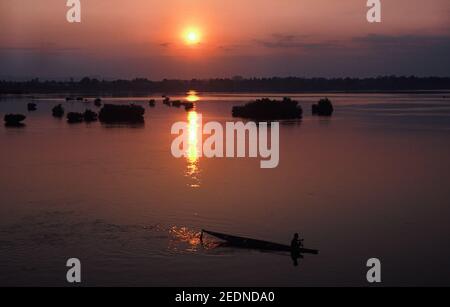 13,04.2014, Muang Khong, Champasak, Laos - EIN hölzernes Kanu, das gegen den Sonnenaufgang über dem Mekong-Fluss von der Don Det-Insel aus gesehen wurde Stockfoto