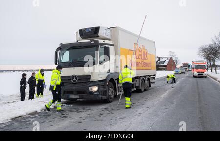 Lehrte, Deutschland. Februar 2021, 15th. Polizisten und Mitarbeiter der Unfallforschungsabteilung der Medizinischen Hochschule Hannover (MHH) stehen nach einem Unfall neben einem LKW auf der Bundesstraße B65. Ein Fußgänger wurde heute Morgen am B65 von einem Lastwagen getroffen und getötet. Bild: Julian Stratenschulte/dpa - ACHTUNG: Das Kennzeichen des am Unfall beteiligten Autos wurde aus rechtlichen Gründen verpixelt/dpa/Alamy Live News Stockfoto
