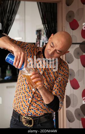 Mann Gießen Bier aus Dose im Wohnzimmer Stockfoto