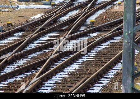Gleise und Schaltpunkt im logistischen Container Bahnhof Für Güterzüge im Winter mit etwas weißem Schnee dazwischen Die Schienen an einem sonnigen Tag Stockfoto